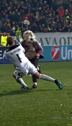 At two seconds, the gray-haired woman in a purple cardigan faces the goalkeeper in white.